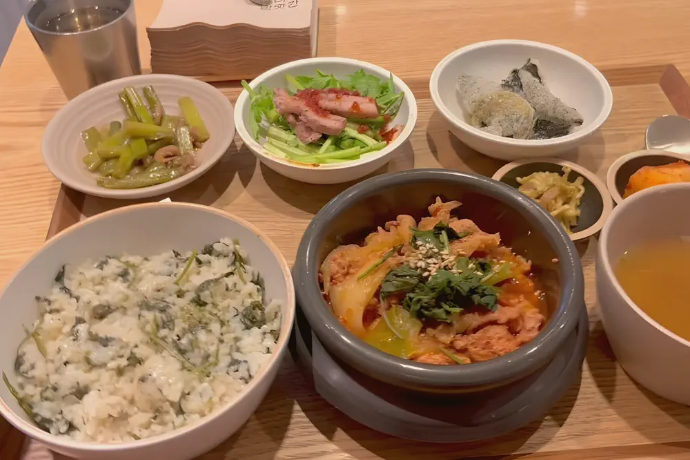 食堂のトレーに並ぶ韓国の定食一膳(ごはん、チゲ、スープと小鉢)
